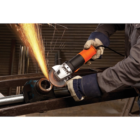 BLACKDECKER G720N angle grinder in use, cutting metal pipe with sparks flying, worker wearing gloves.