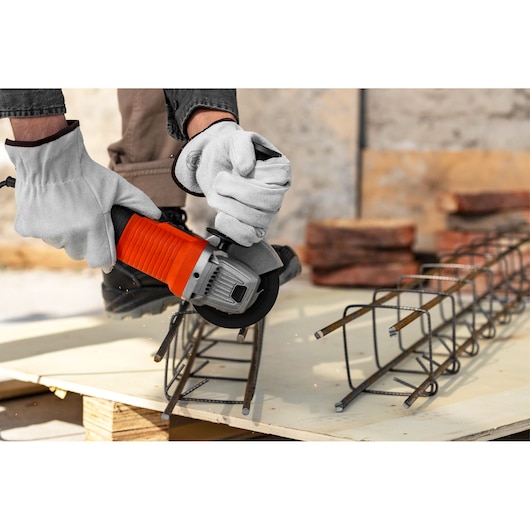 BLACKDECKER G720X angle grinder cutting metal rebar, close-up, worker hands with gloves.