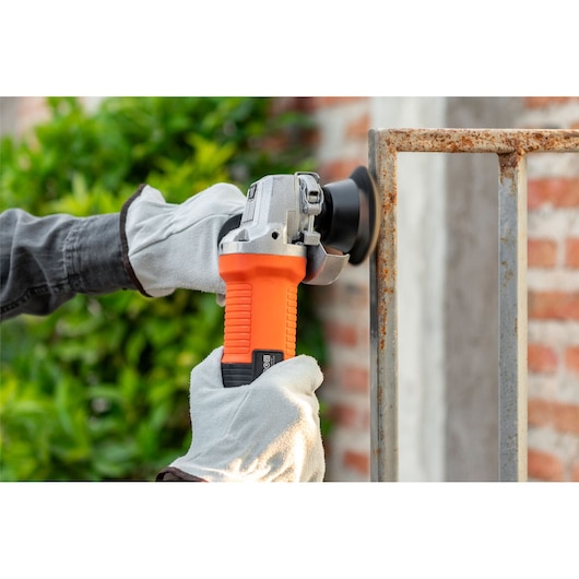 Photo of BLACKDECKER G720X orange angle grinder being used on rusty metal outdoors.