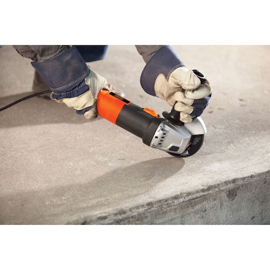 BLACKDECKER G720 angle grinder in use, orange and black body, grinding concrete surface.