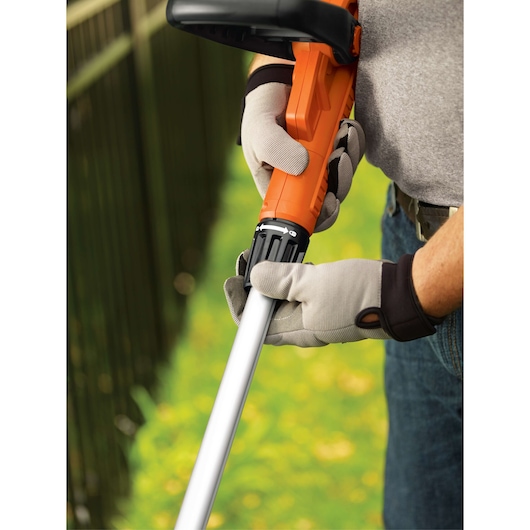 Photo of BLACKDECKER GH900 string trimmer being adjusted by gloved hands outdoors.