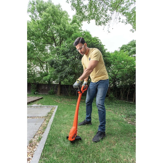 BLACKDECKER GL350 orange electric string trimmer used on grass in a garden.