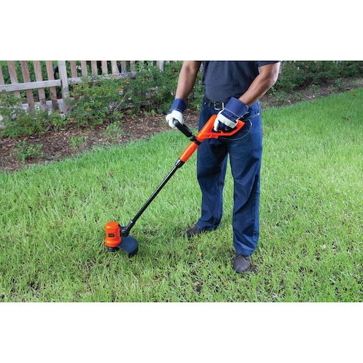 Photo of BLACK+DECKER GL600N grass trimmer being used on a lawn, showing orange and black design.