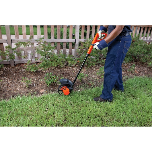 BLACKDECKER GL600N lawn edger being used to trim grass along a garden border.