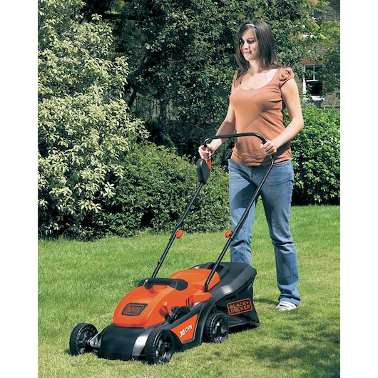 Photo of BLACK+DECKER GR3000 lawn mower in use, orange and black design, on grass.