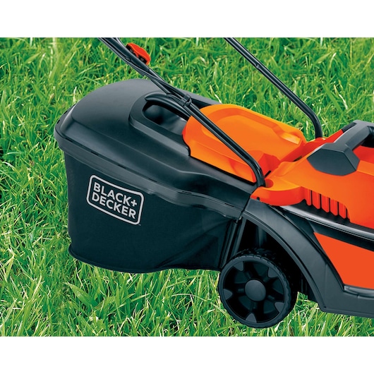 Photo of BLACK+DECKER GR3400 lawn mower side view showing black grass bag and orange body on green grass.