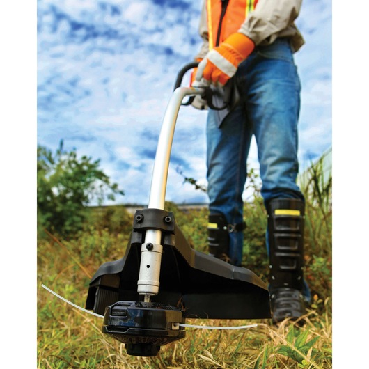 BLACKDECKER GST26 grass trimmer in use outdoors, close-up of cutting head in tall grass.