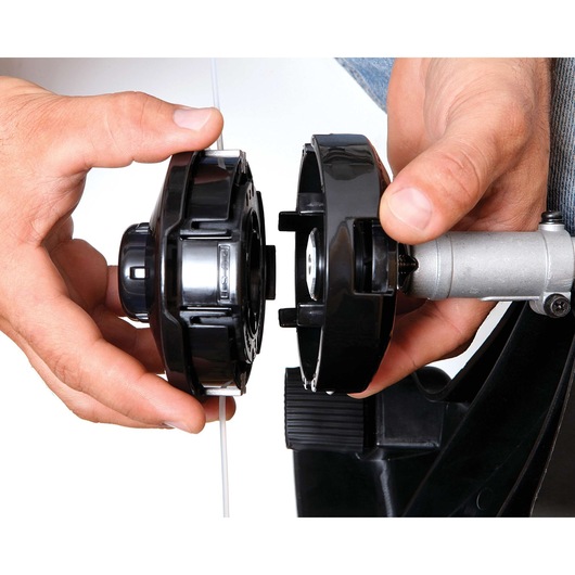 BLACKDECKER GST26 string trimmer spool being installed, close-up of hands assembling black trimmer head.