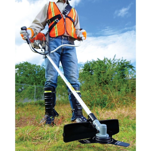 BLACK+DECKER GST33 brush cutter in use outdoors by worker in safety gear, close-up view of cutting head.