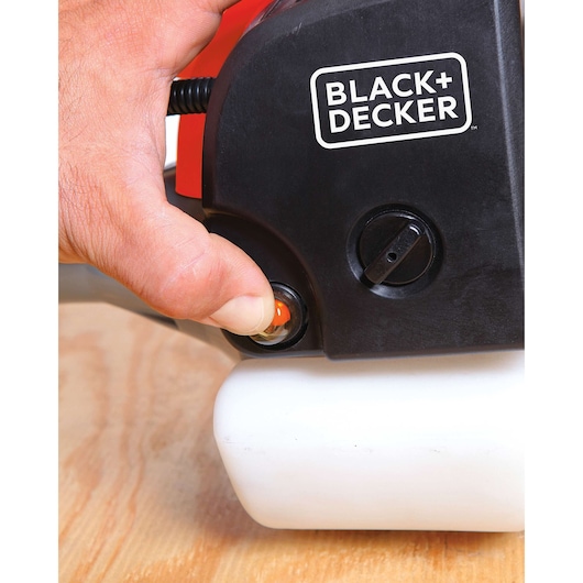 BLACK+DECKER GST33 grass trimmer close-up, hand pressing primer bulb on black and white housing.