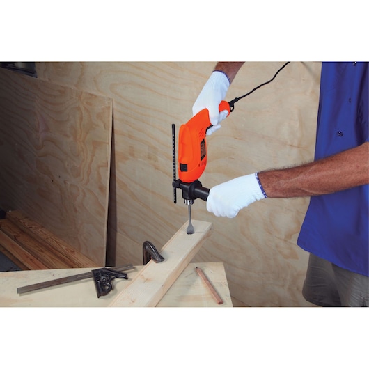 Photo of BLACKDECKER HD555 drill being used on wood, handheld with white gloves in workshop setting.