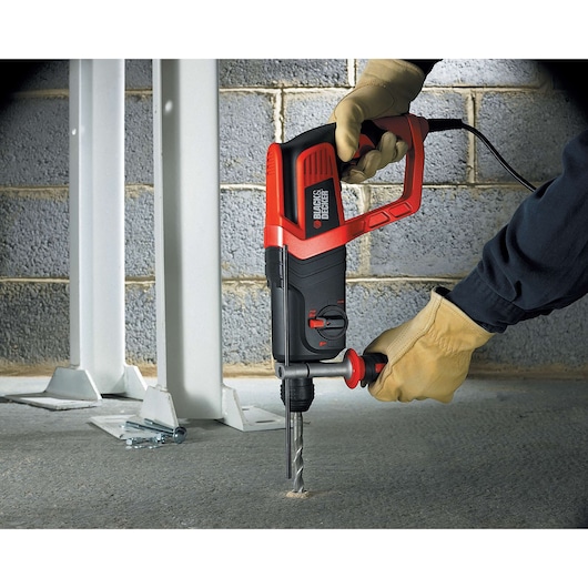 BLACKDECKER KD975KA rotary hammer drill used on concrete floor near steel beams, close-up view.
