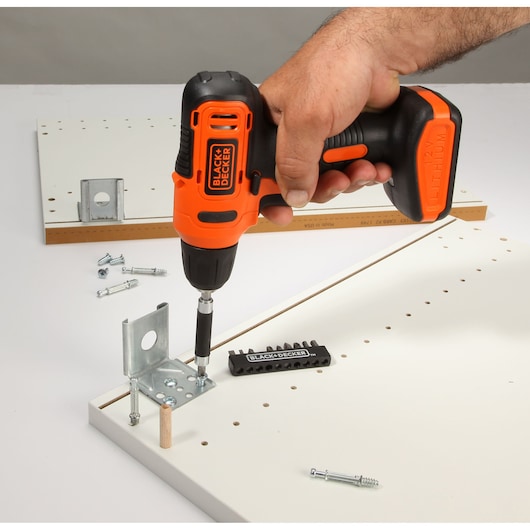 Photo of BLACK+DECKER LD12SP cordless drill being used to assemble white furniture panel with screws and bracket.