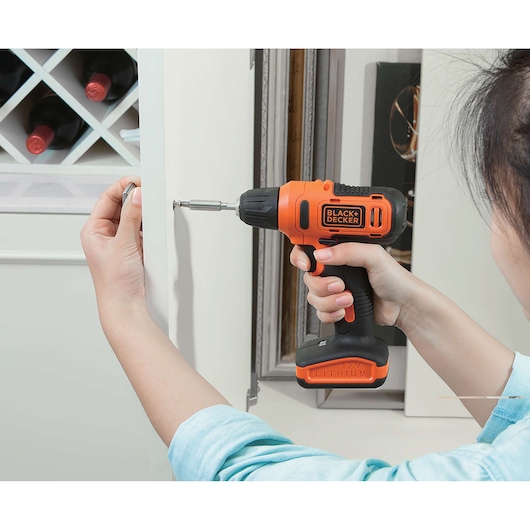 BLACKDECKER LD12S cordless drill being used to install a screw in a cabinet door, close-up action.