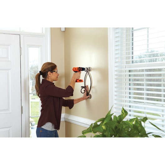 Photo of BLACKDECKER LDX172PK drill being used to mount a decorative metal bracket on an indoor wall.
