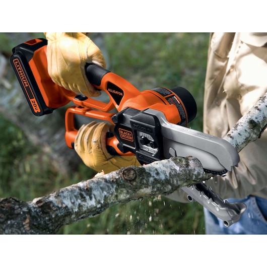 BLACKDECKER LLP120 orange cordless alligator lopper cutting tree branch outdoors, side view.