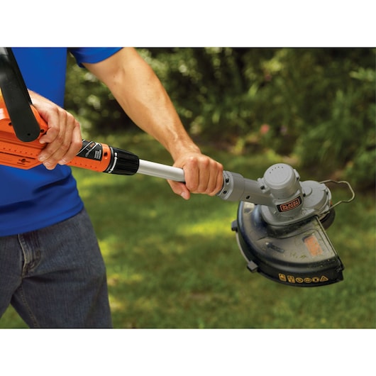 BLACKDECKER LST300 string trimmer in use on lawn, close-up of handle and cutting head.