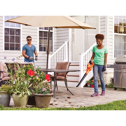 BLACKDECKER LSW221 leaf blower in use on patio with plants, outdoor furniture, umbrella, and grill.