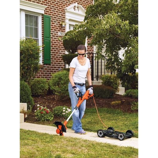 BLACKDECKER MTE912 lawn trimmer and mower in use on grass in front of house, orange and black design.