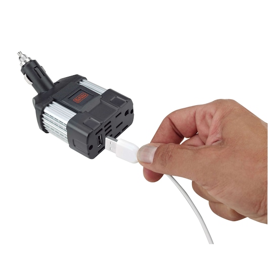 BLACKDECKER PI100LA car power inverter with USB port, hand plugging in cable, photography, white background.