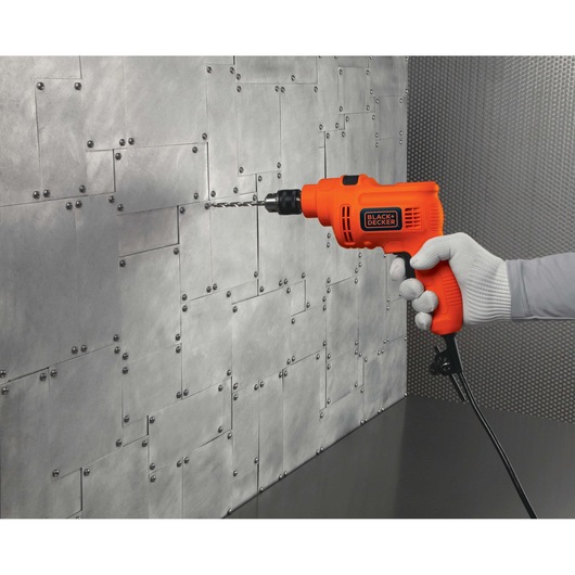 Photo of BLACKDECKER TP550 orange electric drill used on a metal wall, side angle.
