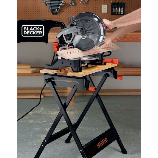 BLACK+DECKER WM125 folding workbench with miter saw cutting wood, side angle view in workshop.